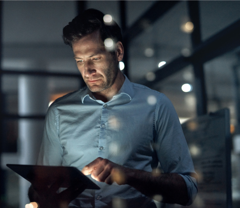White male in dark room reviewing information on a tablet